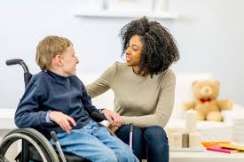 A woman is sitting down talking to a child in a wheelchair.
