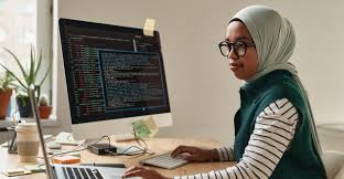 A woman is sitting in an office setting in front of a computer